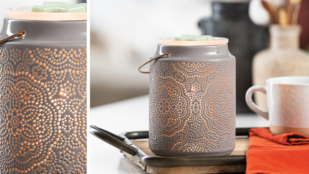 The Scentsy Aziza warmer shown sitting on a countertop, it's inner bulb glowing. 