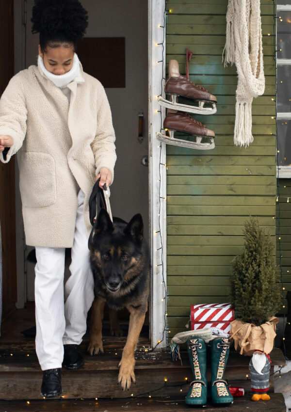 A woman, bundled in a coat and scarf, and her German shepherd step from her front door into the wintery air.