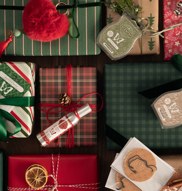 Scentsy Charm Clips, Wax Bars, Scent Circles, and Room Sprays, and other Scentsy Stocking Stuffer products laid out on top of beautifully wrapped Christmas Presents.