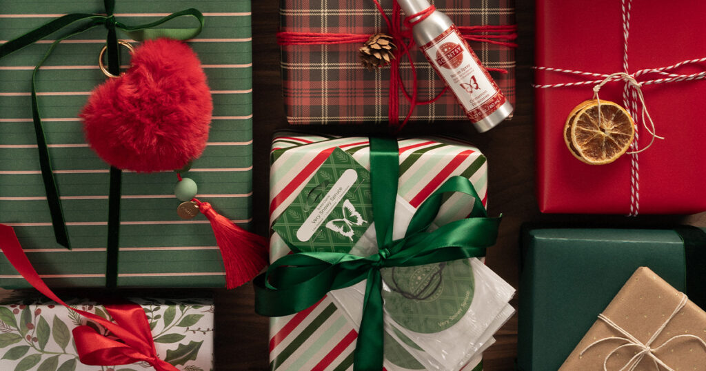The Red Heart Scentsy Charm Clip, Scentsy Room Sprays, and Scent Circles sit on top of traditionally wrapped Christmas packages.