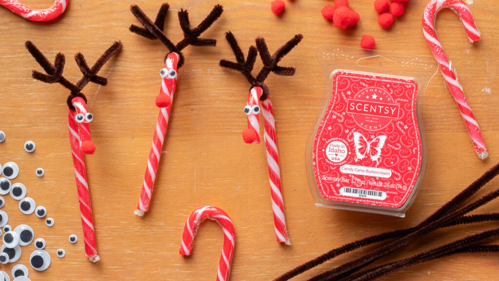 The Scentsy Candy Cane Buttercream Wax Bar next to little DIY candy cane reindeer ornaments. made from pipe cleaners, google eyes, and pom poms.