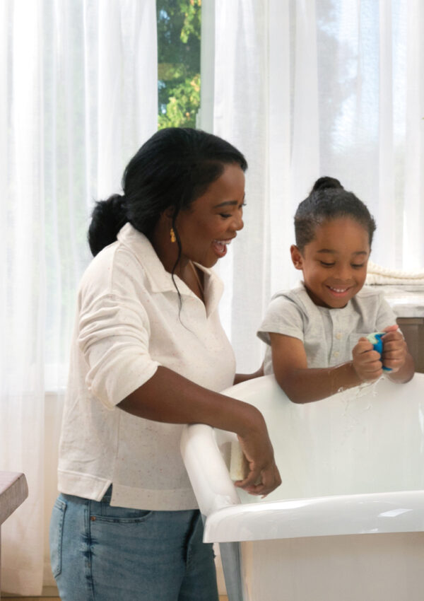 A mother and daughter use Scentsy Bathroom Cleaner to clean a tub together.