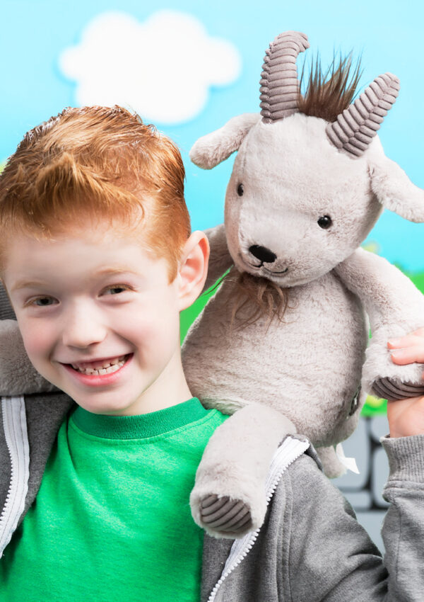 A young boy, smiling and holding Glendon the Goat Scentsy Buddy on his shoulders.