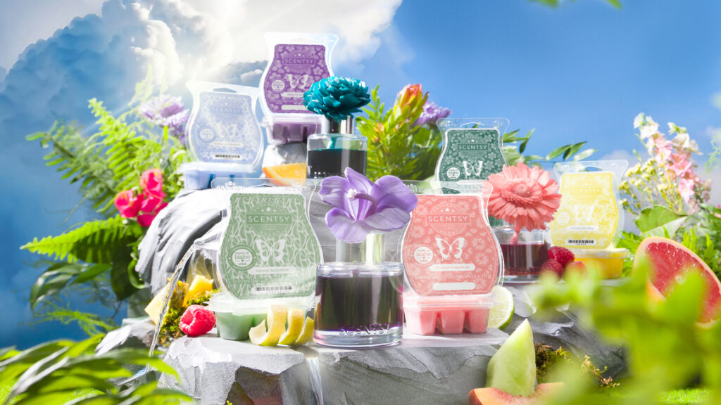 The Scentsy Flower and Garden 2025 collection of fragrance flowers and wax bars displayed with greenery, flowers, and blue skies.