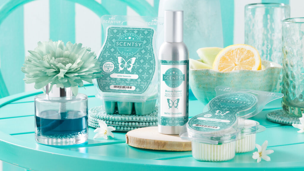 Scentsy Wild Side fragrance flower, wax bar, room spray, and pods decorate a teal-blue table with cups, bowls and other set dressings in mono-chrome teal.