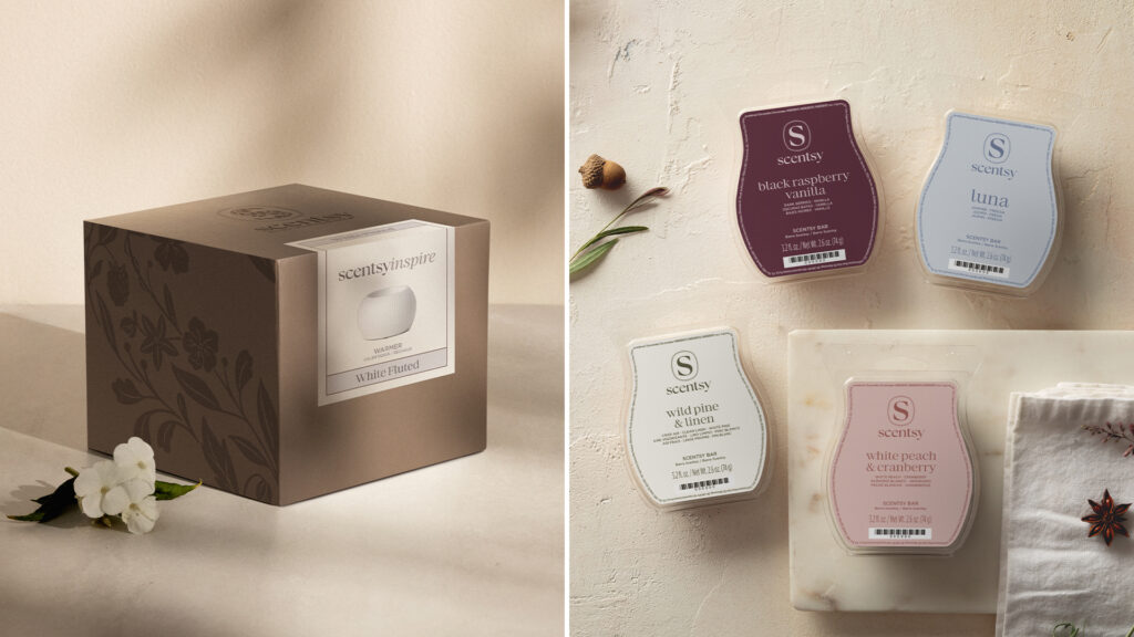 A Scentsy Warmer and Scentsy Luna, Black Raspberry Vanilla, Wild Pine & Linen, and White Peach & Cranberry are depicted in new boxes and with new labels depicting the rebrand to monochrome color schemes and subdued elegance.