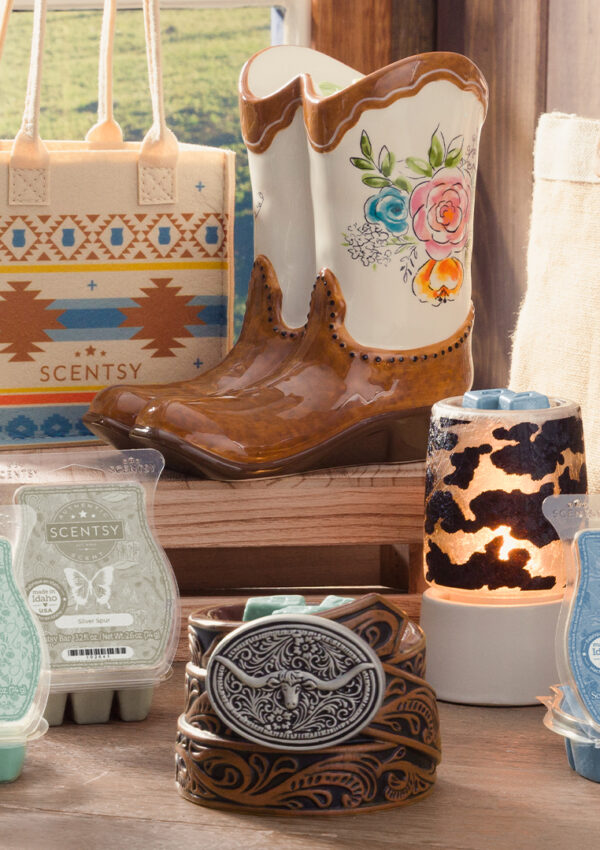 The Scentsy Wild Flowers and Wild Horses collection of wax bars and warmers is displayed in a farmhouse-style set in front of a window looking out over a pasture.