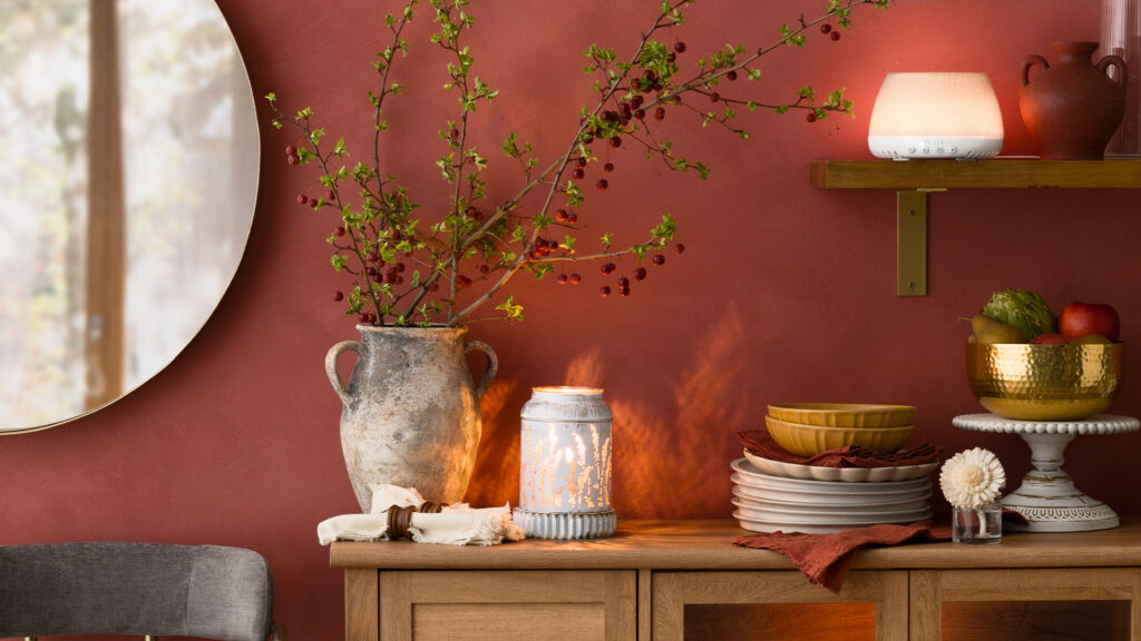 A home dining room with warm red and brown tones, rustic decor aestetics, white tableware, a fragrance flower, and a Scentsy Air Quad.