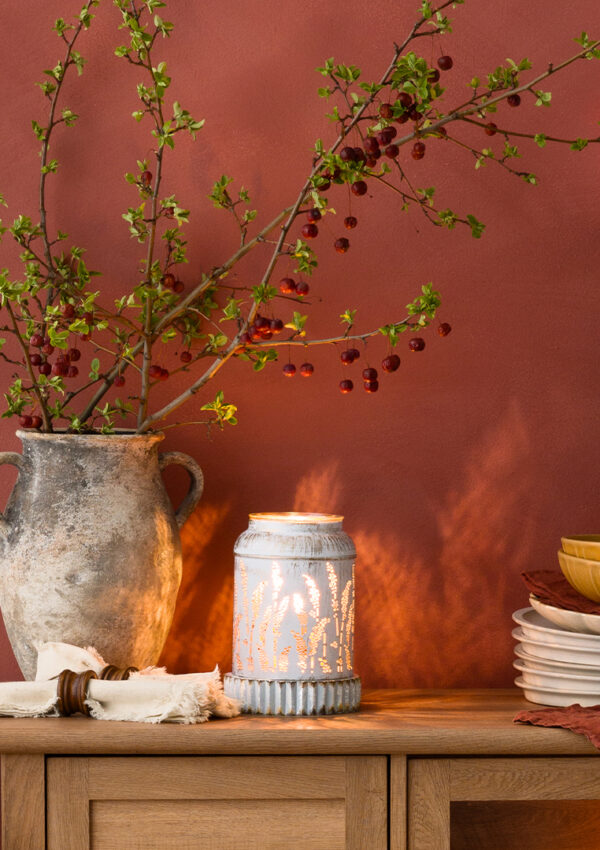 A home dining room with warm red and brown tones, rustic decor aestetics, white tableware, a fragrance flower, and a Scentsy Air Quad.