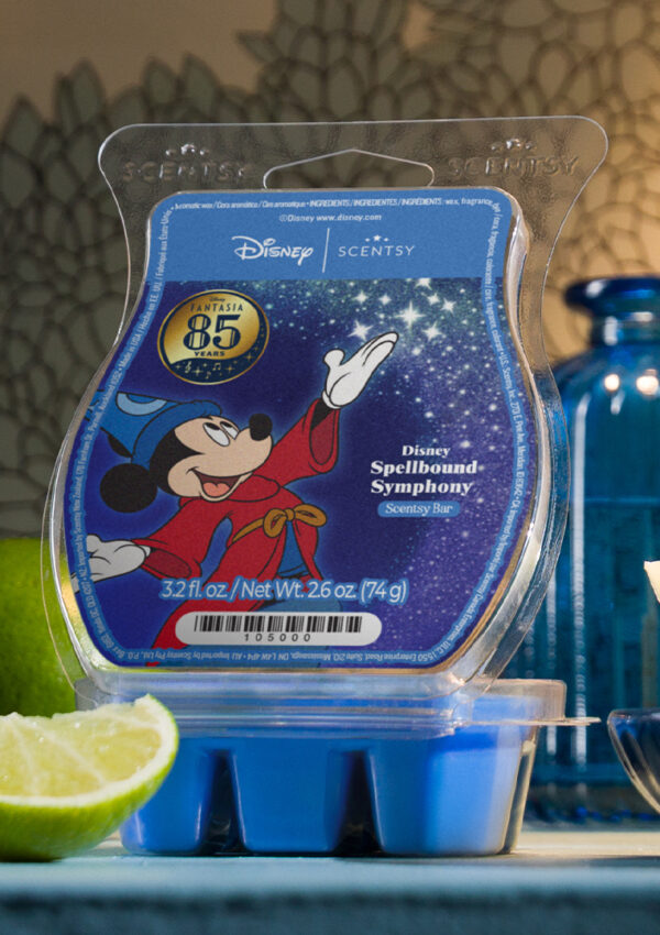 The Disney's Fantasia Mickey Mouse Sorcerer's Apprentice Wax Warmer sits on a wooden end table beside the Spellbound Symphony Wax Bar and the Mickey Mouse Sorcerer's Apprentice plush wearing the legendary, blue, moon and star wizard's hat.