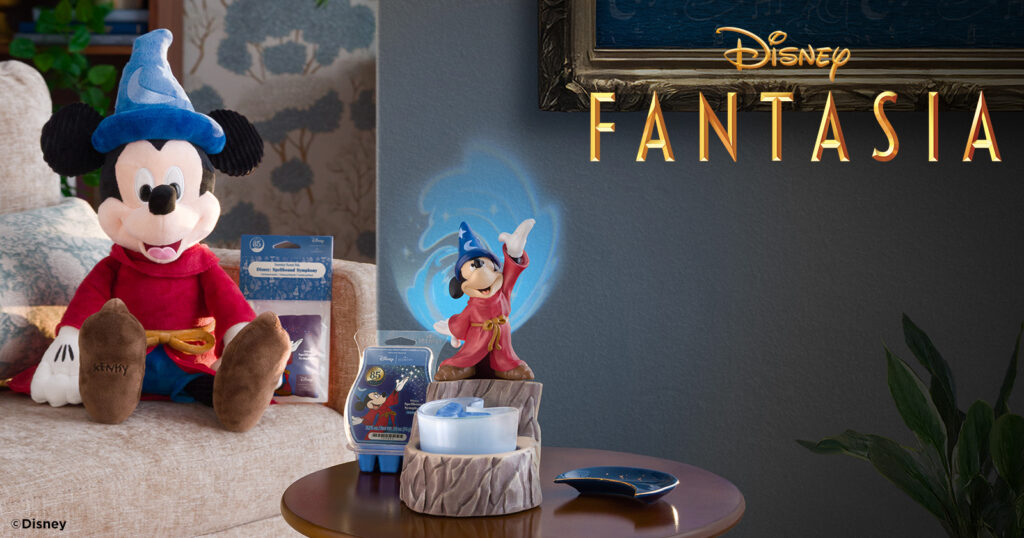 The Disney's Fantasia Mickey Mouse Sorcerer's Apprentice Wax Warmer sits on a wooden end table beside the Spellbound Symphony Wax Bar and the Mickey Mouse Sorcerer's Apprentice plush wearing the legendary, blue, moon and star wizard's hat.