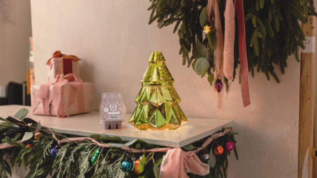 Scentsy's Christmas tree shaped Warmer of the Month, Light up the Season, sits on a mantle beside decorated garlands, a Christmas wreath, and the Scentsy Scent of the Month, Cocoa Cashmere. 