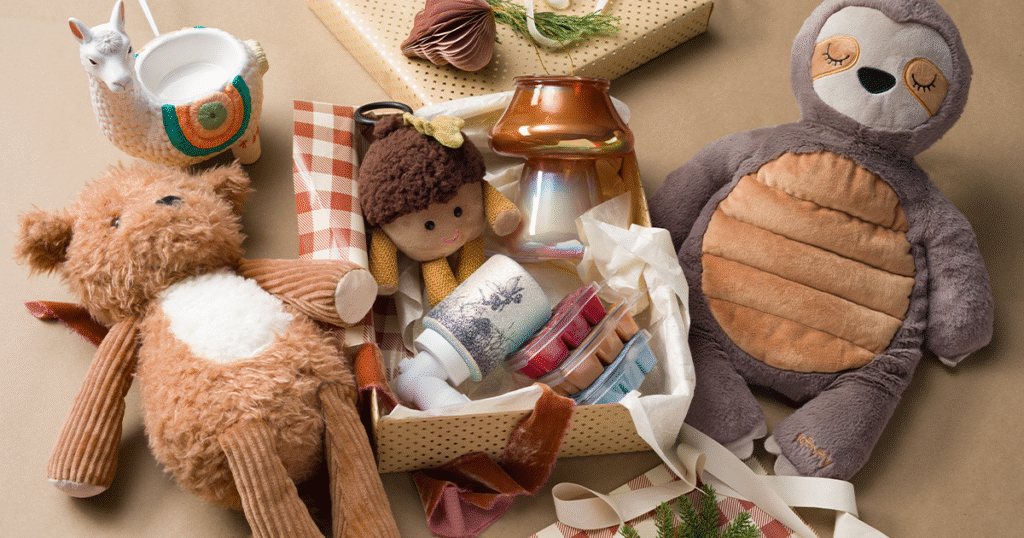 A Scentsy Gift Set Christmas gift box full of Scentsy Plush and Buddy Clips, Wax Warmers, Wax Bars, and Mini Warmers, all wrapped in cream and tand tissue paper and Christmas wrapping paper.