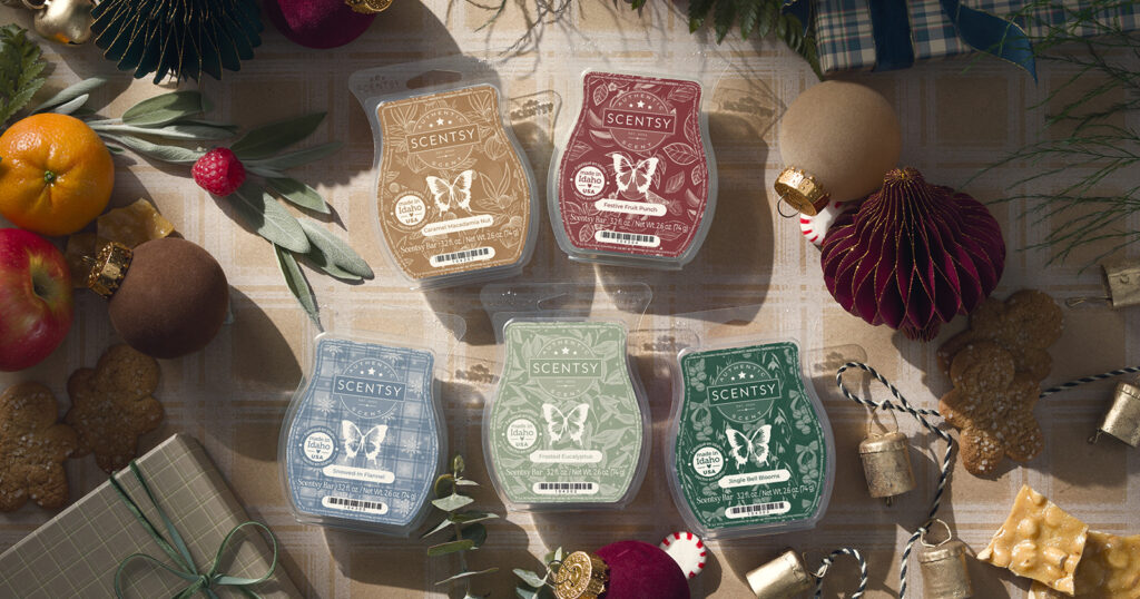 All the Scentsy Wax Bars from Scents of the Season surrounded by Christmas ornaments, holly, citrus fruits, peanut brittle, and peppermint candies. 