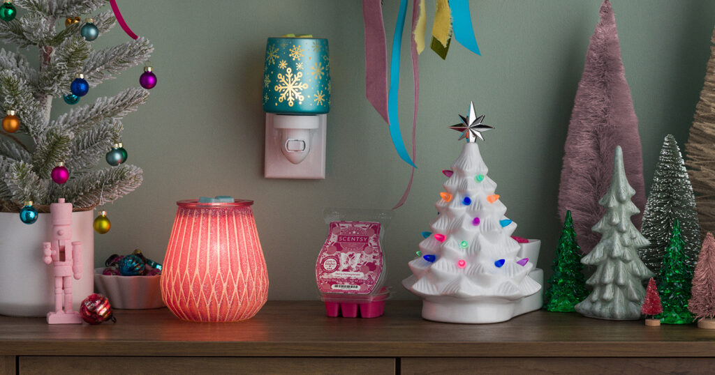 Vintage, playful wax warmers and wax melts from Scentsy's Merry and Bright Collection sits on a wooden table full of Christmas tree and ornamental decor.