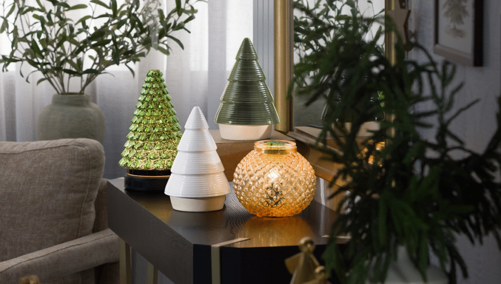Scentsy Oil Diffusers and Wax Warmers, three shaped like Christmas Trees and one shaped like a golden ornament, sit on a living room side table.