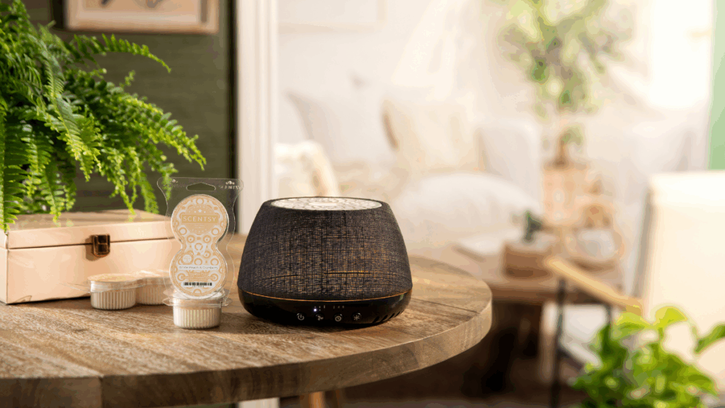 The Scentsy Air Quad sits on a tabletop in a living room decorated with house plants and a beige boho theme. 