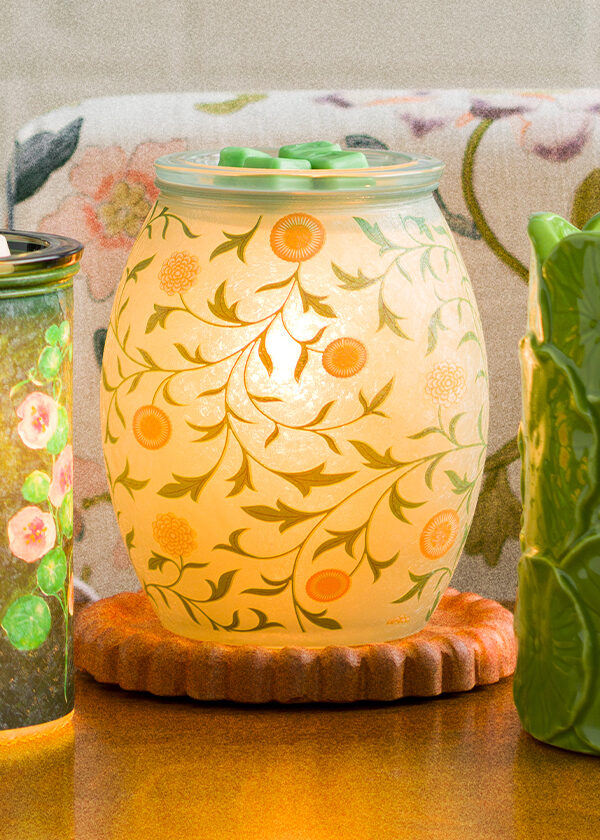 Three Warmers from Scentsy's March Monthly Edit are displayed on a side table in a living room setting.