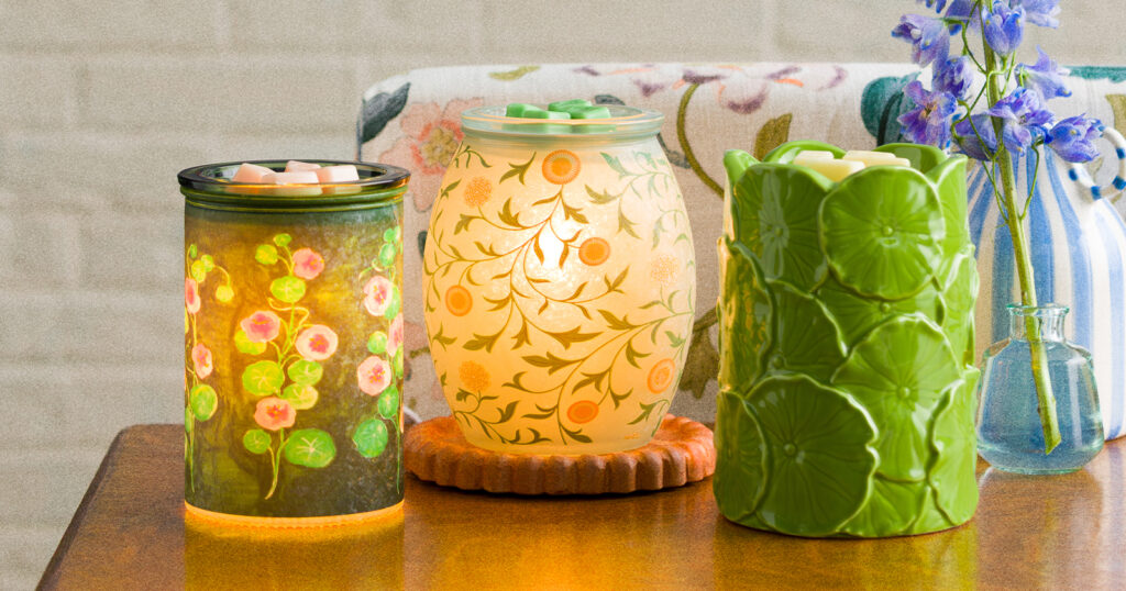 Warmers from Scentsy's March Monthy Edit are displayed on a table in a living room setting. 
