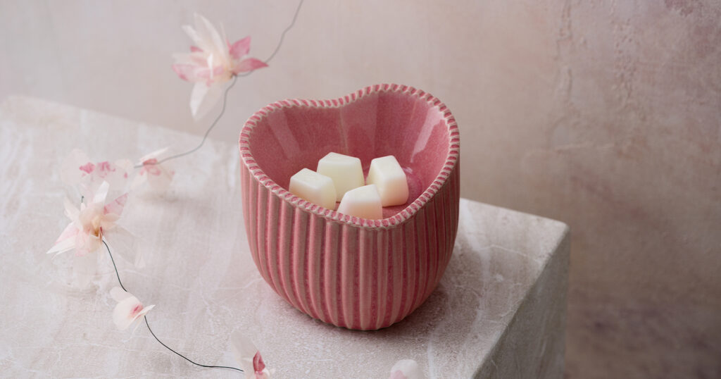 Scentsy's Heart of Hope Warmer raises funds for nonprofits focused on the effects of heart disease. It's displayed with faux florals on a pink marble slab.