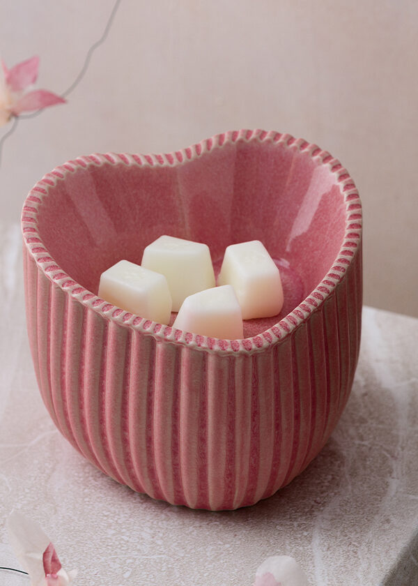 Scentsy's Heart of Hope Warmer raises funds for nonprofits focused on the effects of heart disease. It's displayed with faux florals on a pink marble slab.