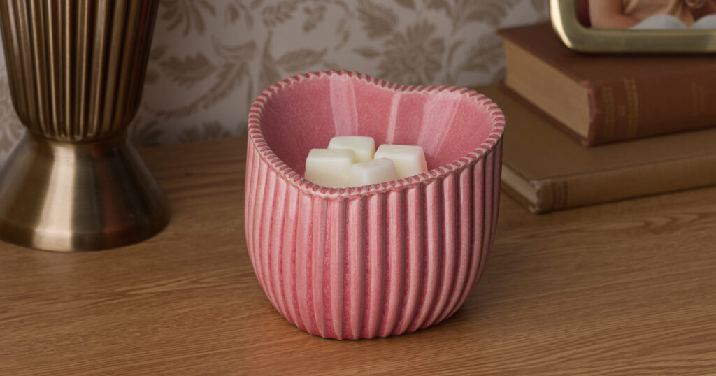 The Heart of Hope Warmer is arranged on a table surrounded by books, photos and a vase.