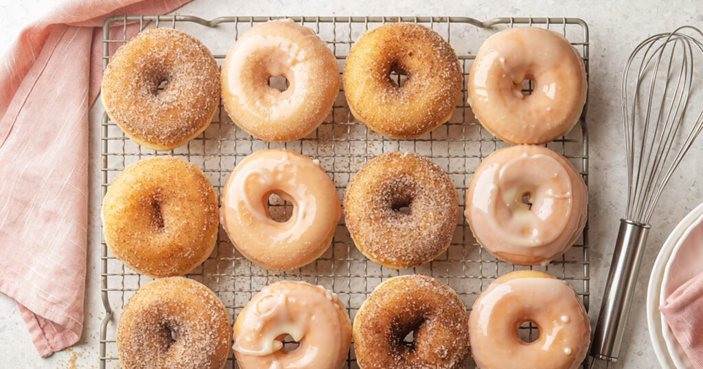 Homemade baked cinnamon sugar and glazed donuts cool on a baking rack.