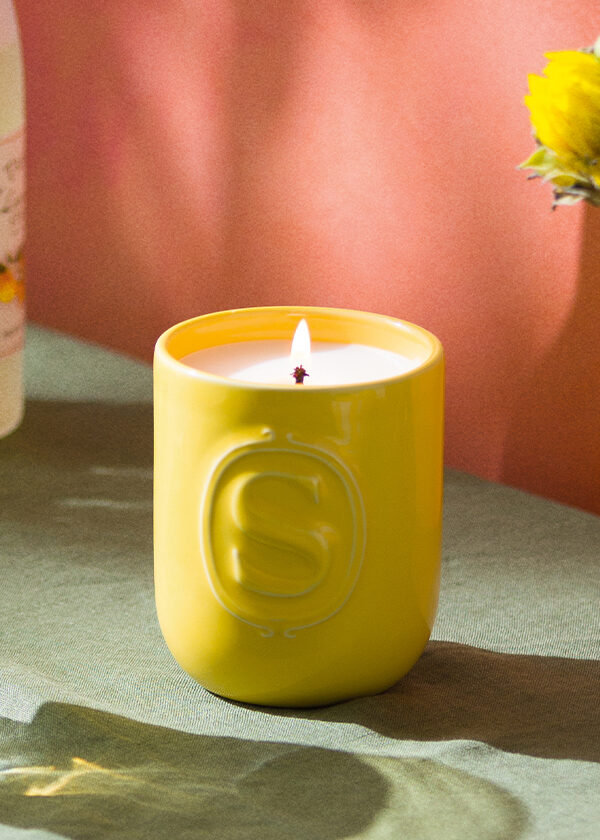 A Limone Fresco Scentsy Candle is lit in a mediterranean kitchen setting with citrus fruits and a fresh beverage.
