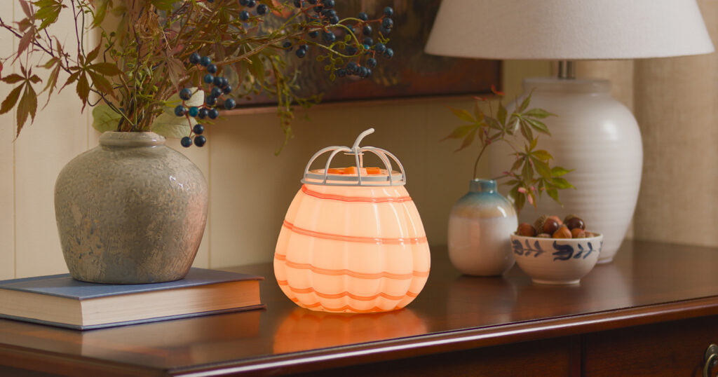 A Cider Swirl Pumpkin Warmer on a hall table, ideal for warming wax melts in cozy fall fragrances.