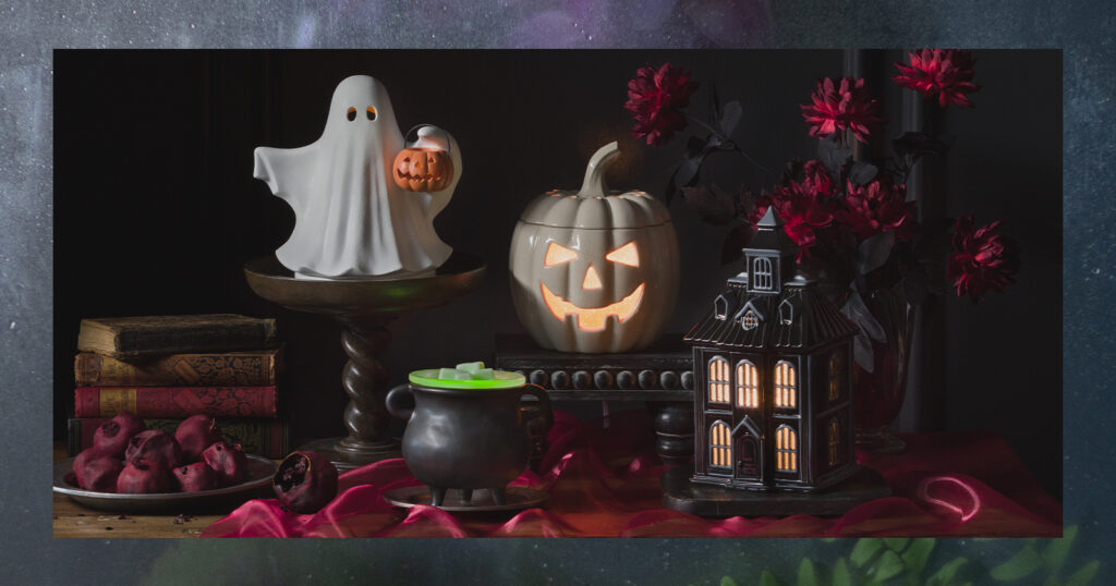 Halloween themed warmers in Scentsy's September Edit are displayed in a dark and opulent setting with red velvet, stacked books and more.