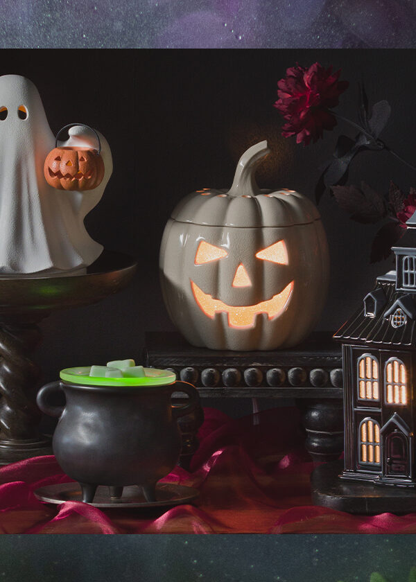 Halloween themed warmers in Scentsy's September Edit are displayed in a dark and opulent setting with red velvet, stacked books and more.